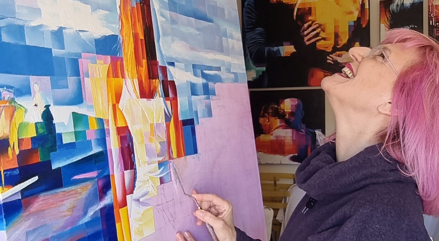 La Gioia di Creare Artista con capelli rosa che dipinge una grande tela colorata, sorridendo in studio.