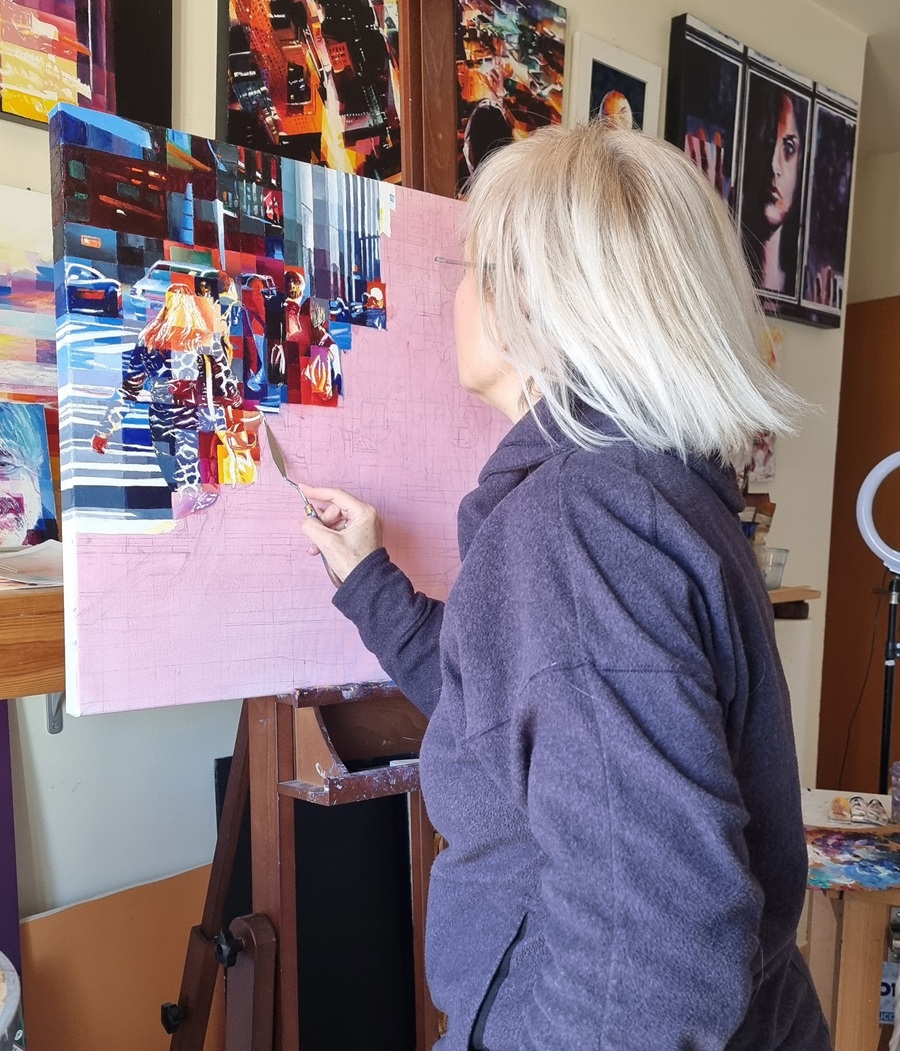 The artist Assunta Cassa at work painting a vibrant urban scene, reflecting the dynamic process of creativity and transformation.