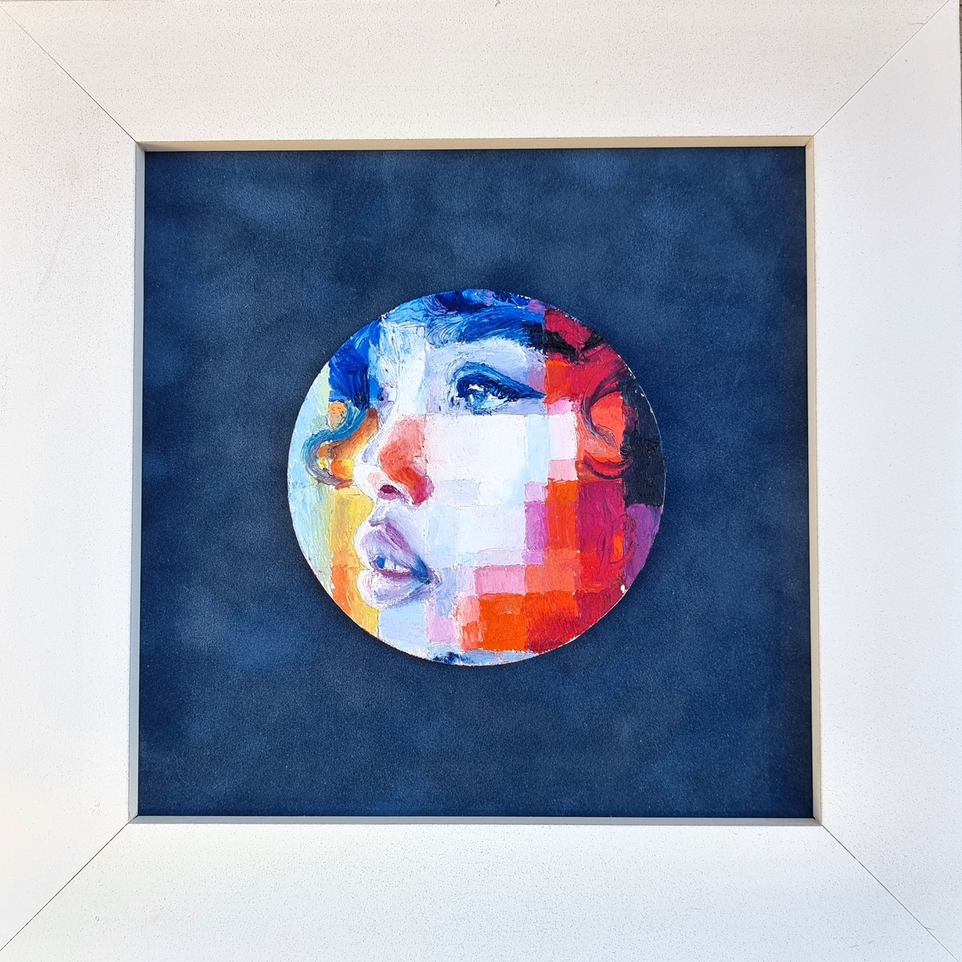 Framed artwork 'Sideral Gaze' by Assunta Cassa displayed against a dark blue background, featuring a vibrant circular portrait with vivid colors capturing the thoughtful expression of a woman.