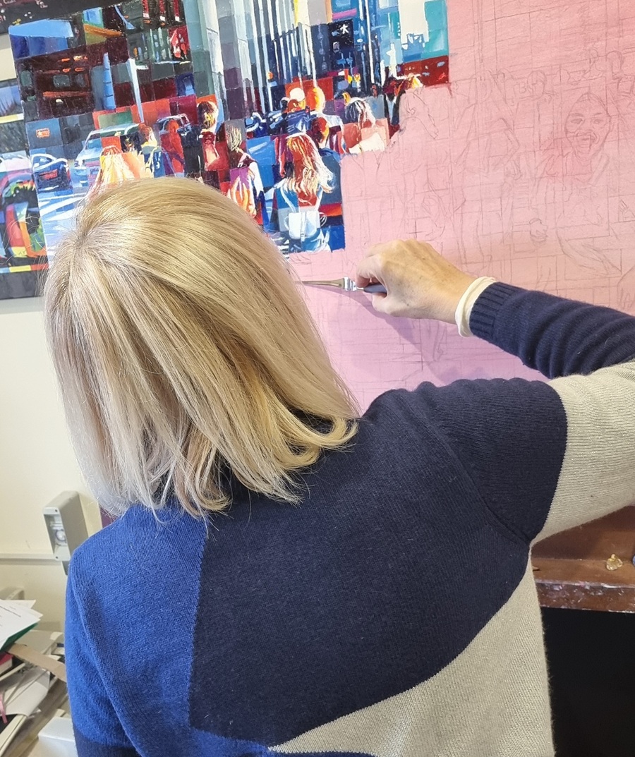 Pittura come meditazione L’artista Assunta Cassa dipinge con la spatola su una tela urbana dettagliata, in un momento di lavoro meditativo e concentrato.
