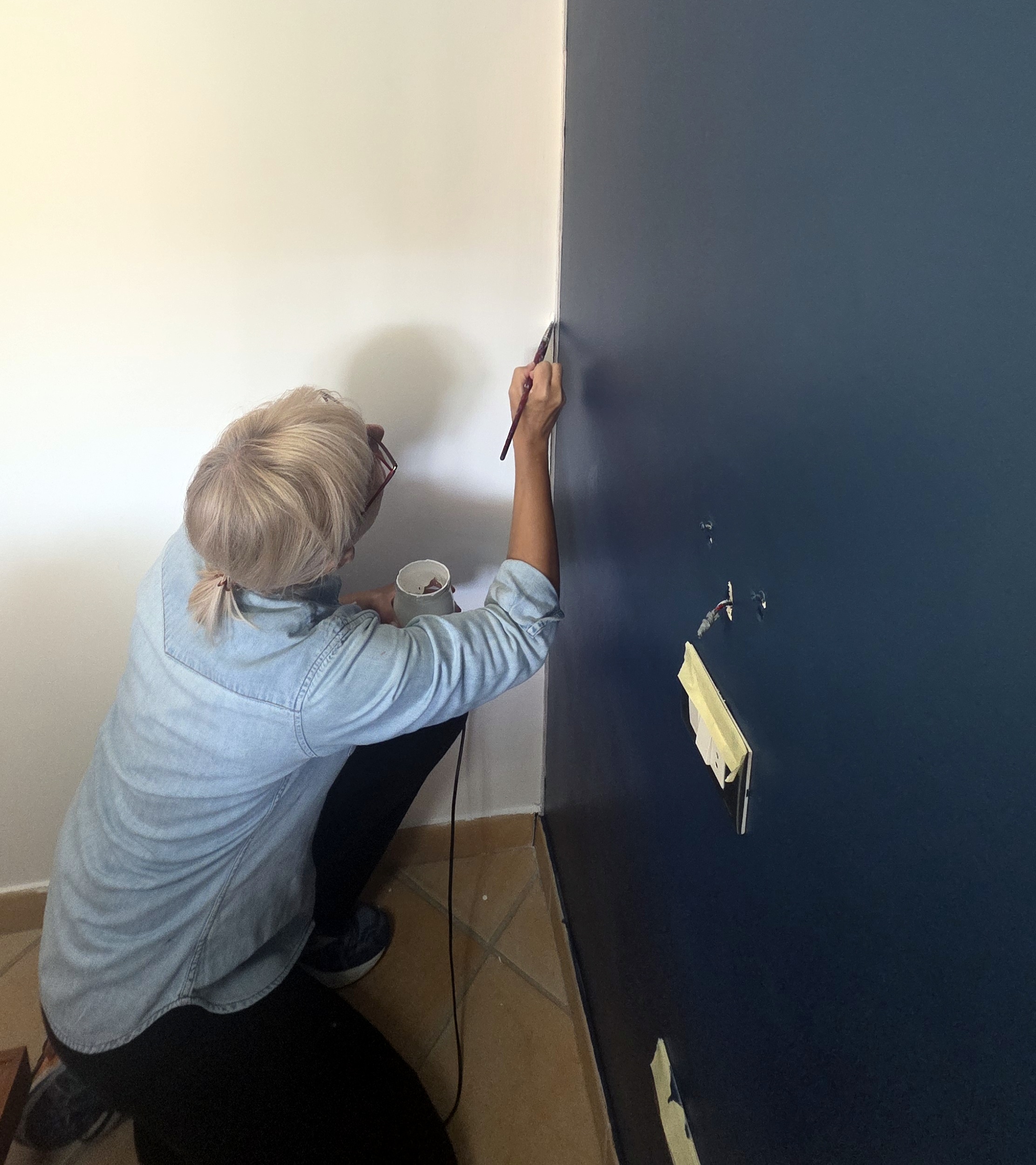 die kraft der farben — Künstlerin streicht eine dunkelblaue Wand