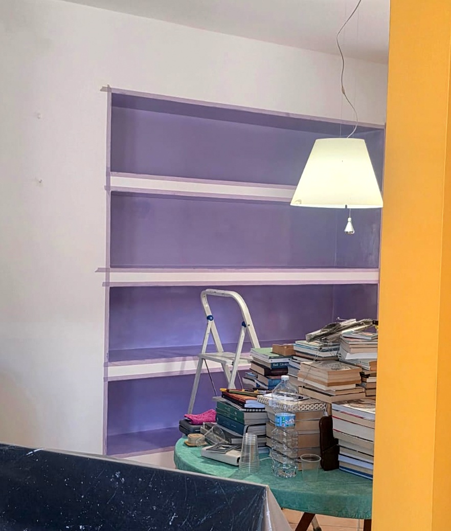 die kraft der farben — violettes Bücherregal während der Arbeit mit Büchern und Leiter