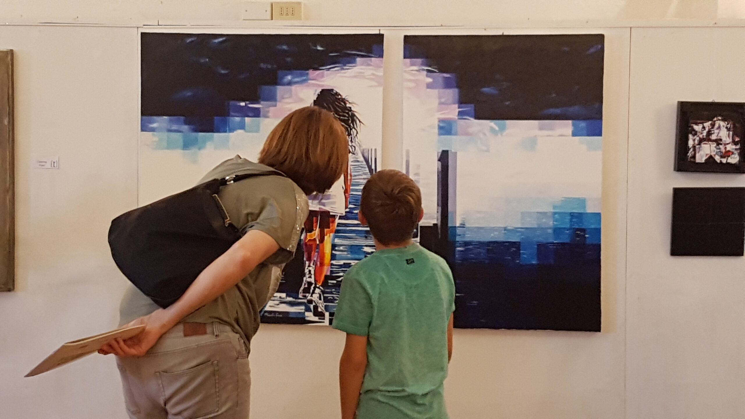 Uno sguardo condiviso — mostra di Assunta Cassa Una donna e un bambino osservano da vicino un dittico di Assunta Cassa durante una mostra, serie Freedom.