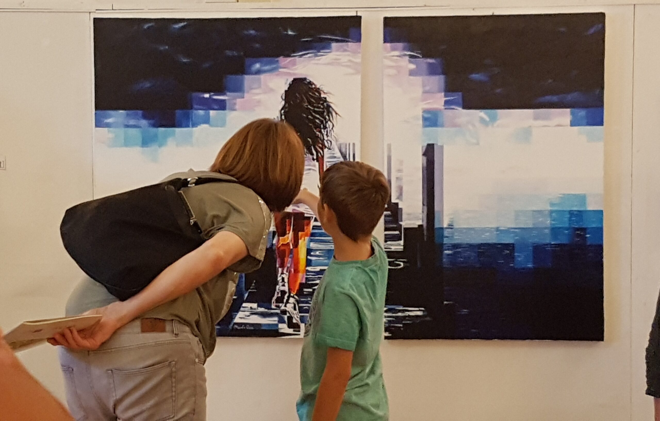 Eine Frau und ein Kind betrachten aufmerksam ein Diptychon von Assunta Cassa bei einer Ausstellung, Serie Freedom.