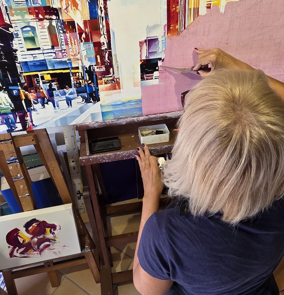 Assunta Cassa in ihrem Atelier beim Malen mit dem Spachtel, von hinten