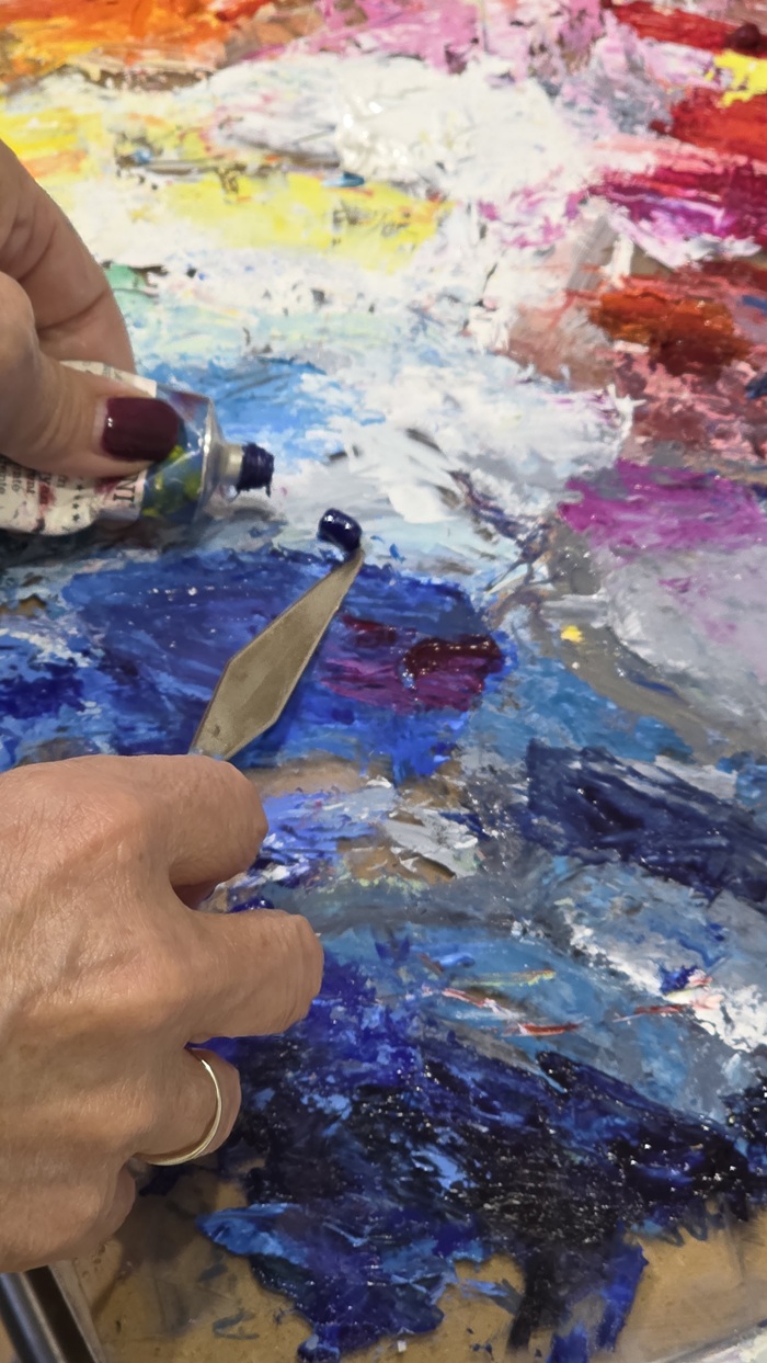 Dettaglio di colori e tavolozza con mani dell'artista Dettaglio di spatola e colori a olio su tavolozza — il gesto pittorico