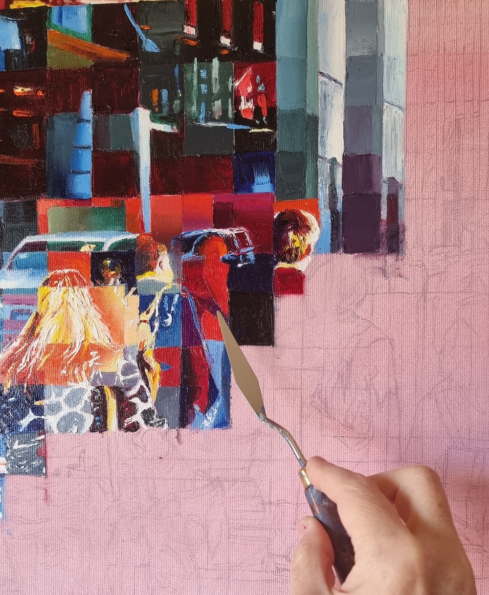 Artist Assunta Cassa's hand holding a palette knife over a work-in-progress canvas, fragmented urban figures on a pink ground, Metropolitan series.